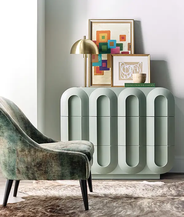 Green fluted console table and accent chair against a pale wall