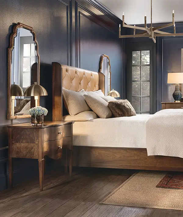 Upholstered bed with a tufted headboard beside a wood nightstand and table lamp