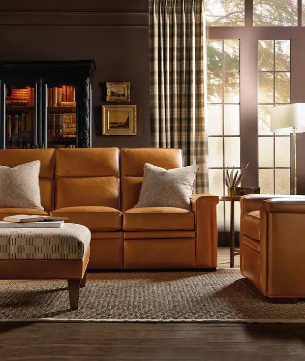 Tan leather reclining sofa and ottoman in a warm den