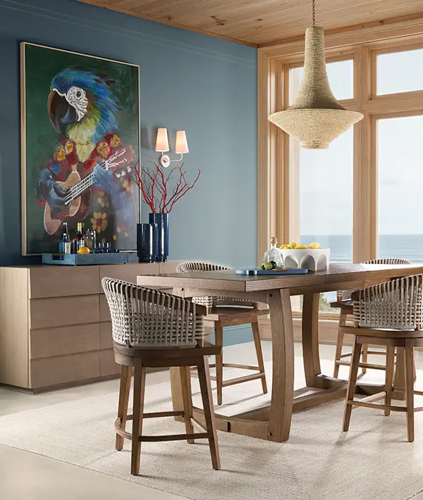 Coastal dining room with a wood table, woven counter stools and an ocean view