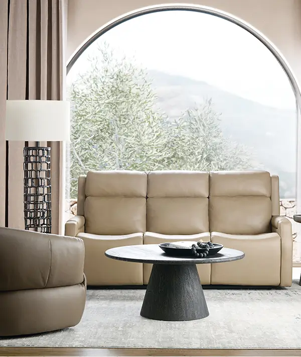 Leather sofa and armchair in a sunlit room with a round arched window