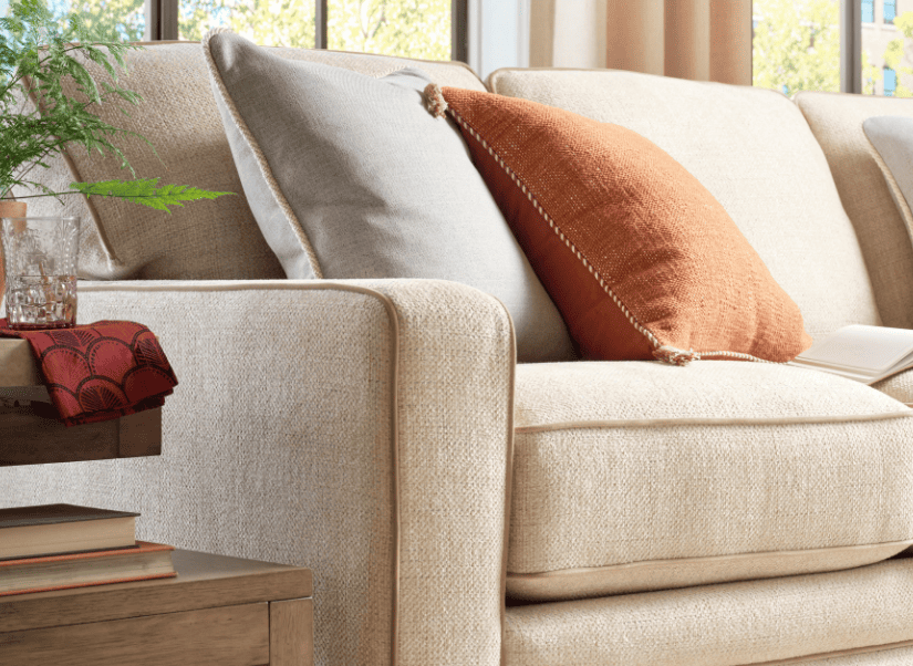 A cream-colored La-Z-Boy sofa with rust and red accent pillows