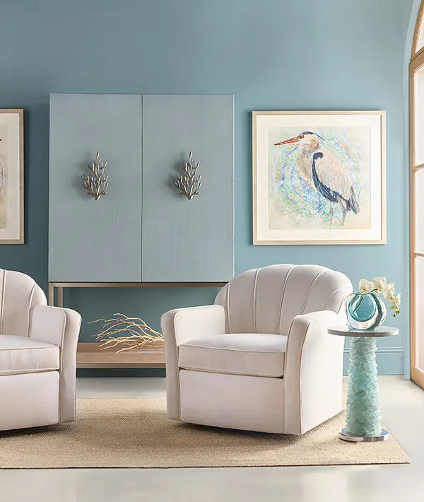 Upholstered swivel chair beside coastal artwork and a ceramic accent table