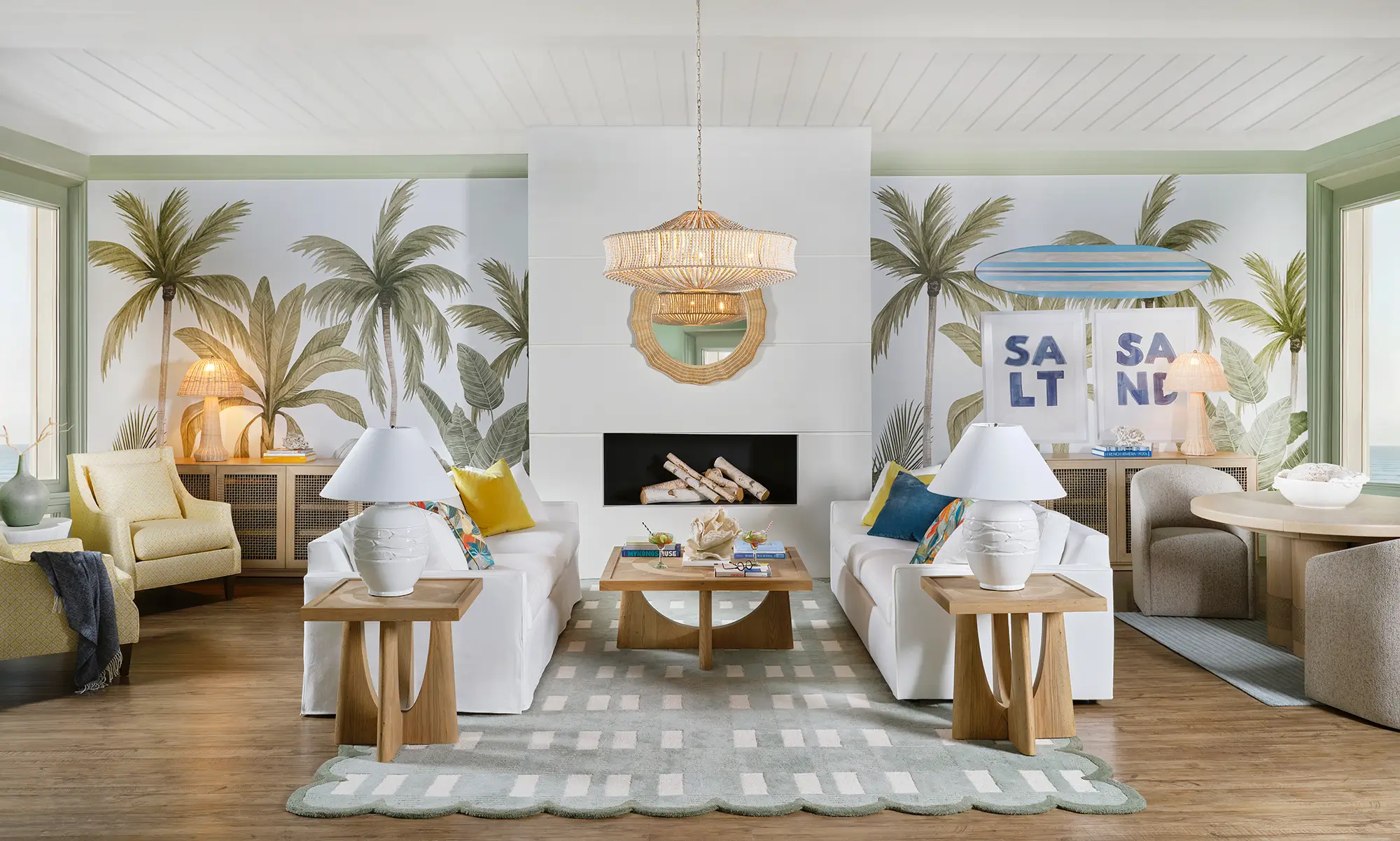 Coastal living room with palm-print walls, white sofas and a woven chandelier